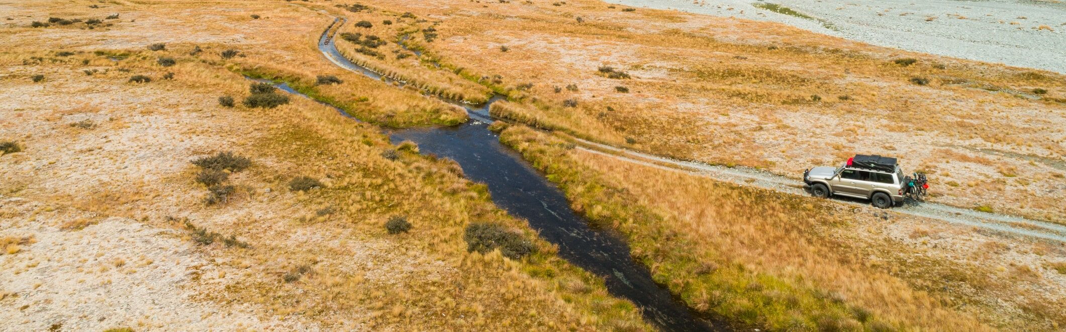 4x4 jeep driving off road about to cross river bed image.