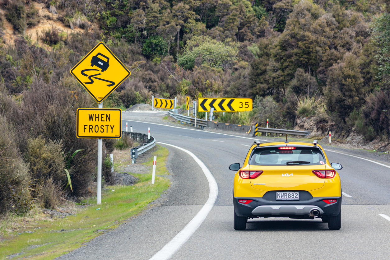 yellow car travelling on road with warning when frosty sign image